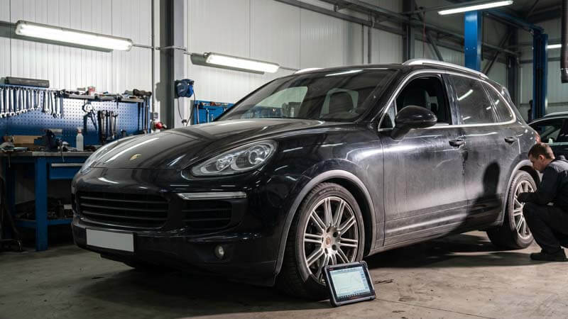 Черный Porsche Cayenne с неисправной пневмоподвеской просел на переднее колесо